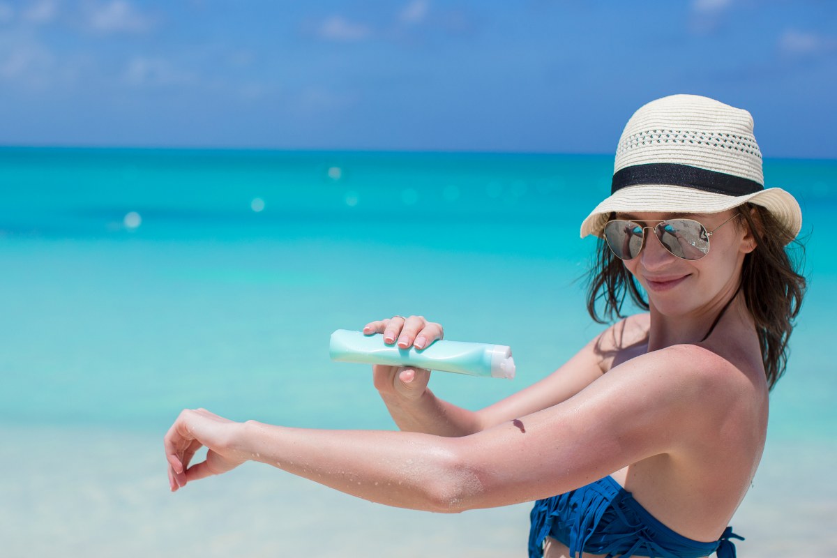 Young woman applying sun cream on beach