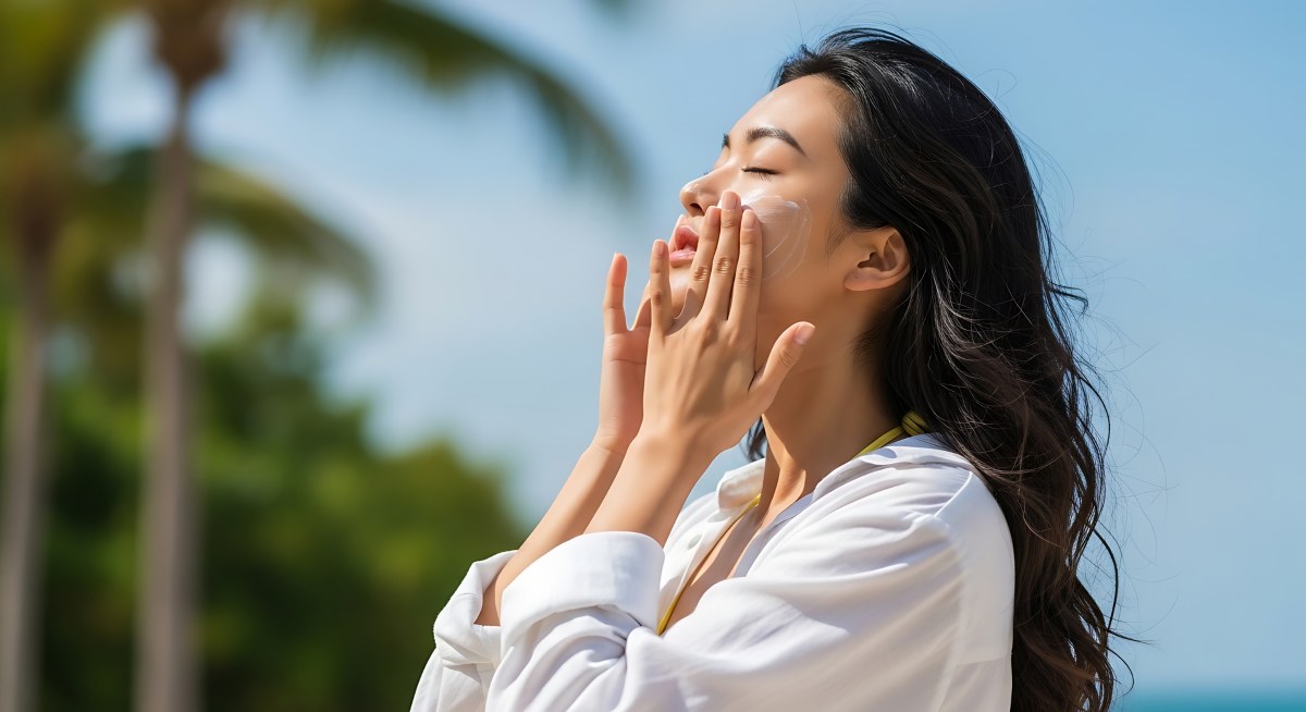 Stunning Beachside Photo of Asian Woman Applying Sunscreen Product